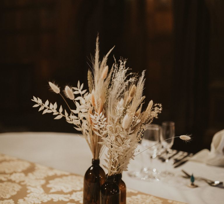 Dried flower centrepiece arrangement in brown bottles 