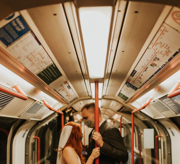 Bride and groom on London underground tube wearing masks on their wedding day 