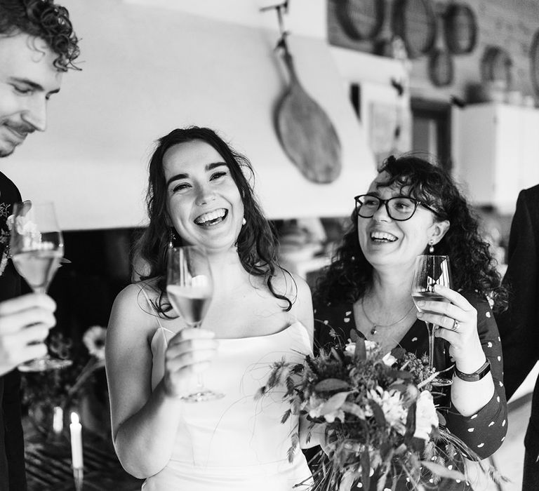 The bride and groom raising a toast with family and laughing