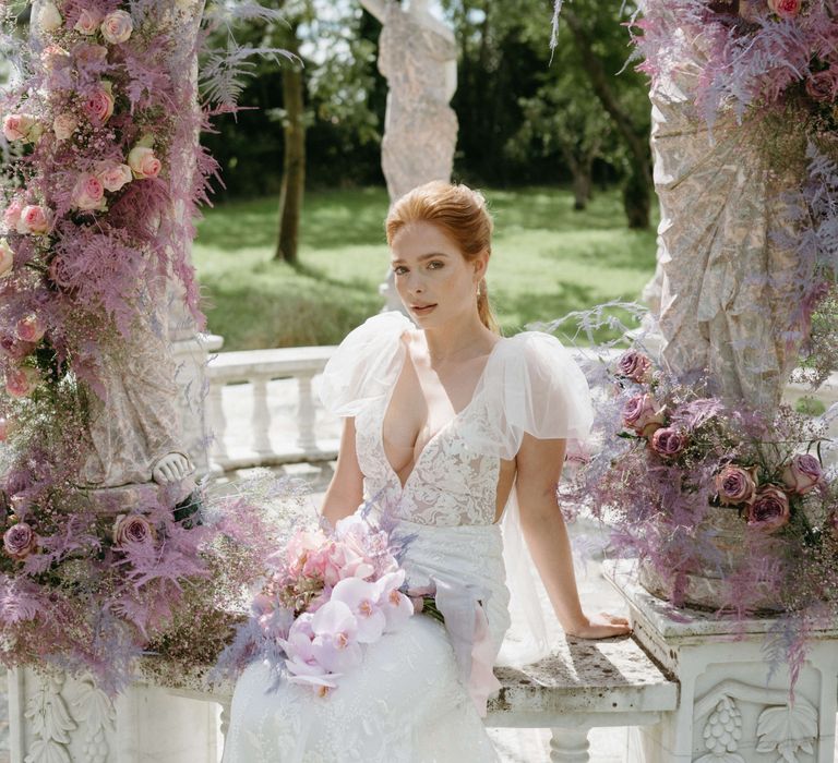 Bride sits in bandstand wearing low cut lace gown