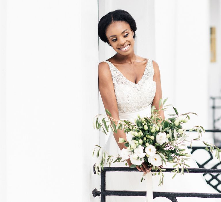 Bride holds floral bouquet and smiles