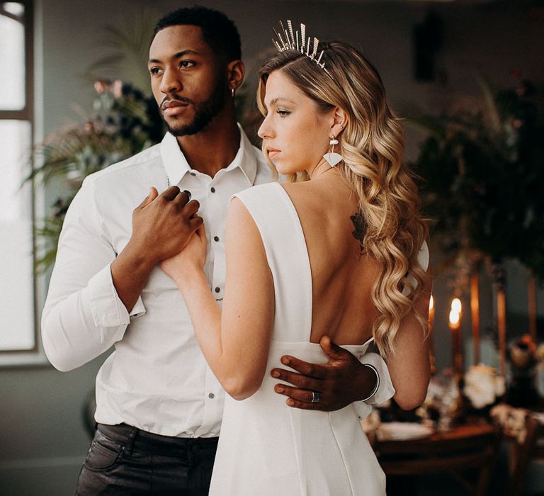 Bride and groom portrait with groom in leather trousers and bride in a fitted wedding dress with low back and long wavy hair 