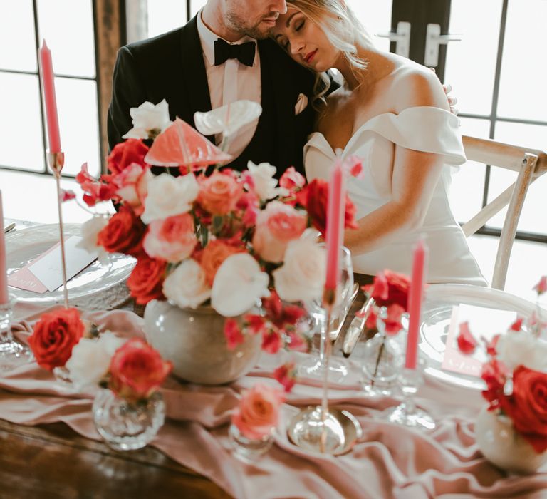 Bride & groom embrace in front of coral florals