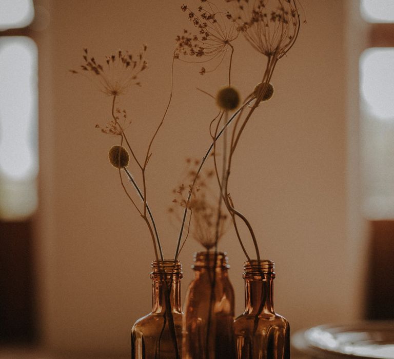 Brown bottles filled with dried flower stems 