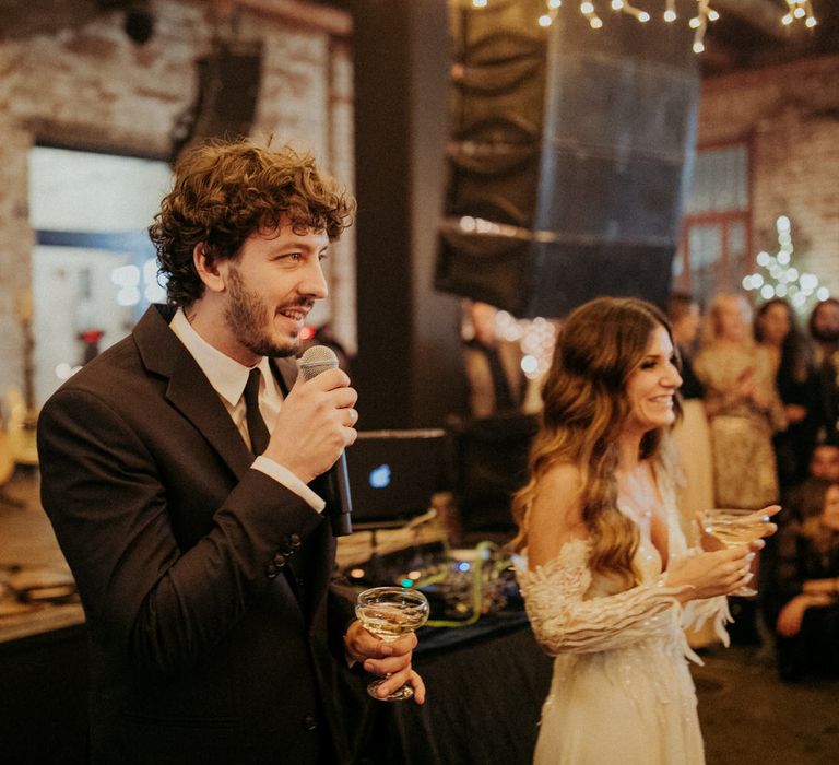 The groom and bride holding a glass of champagne and making speeches at Block 33