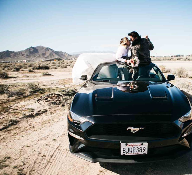 Bride and groom on black Mustang