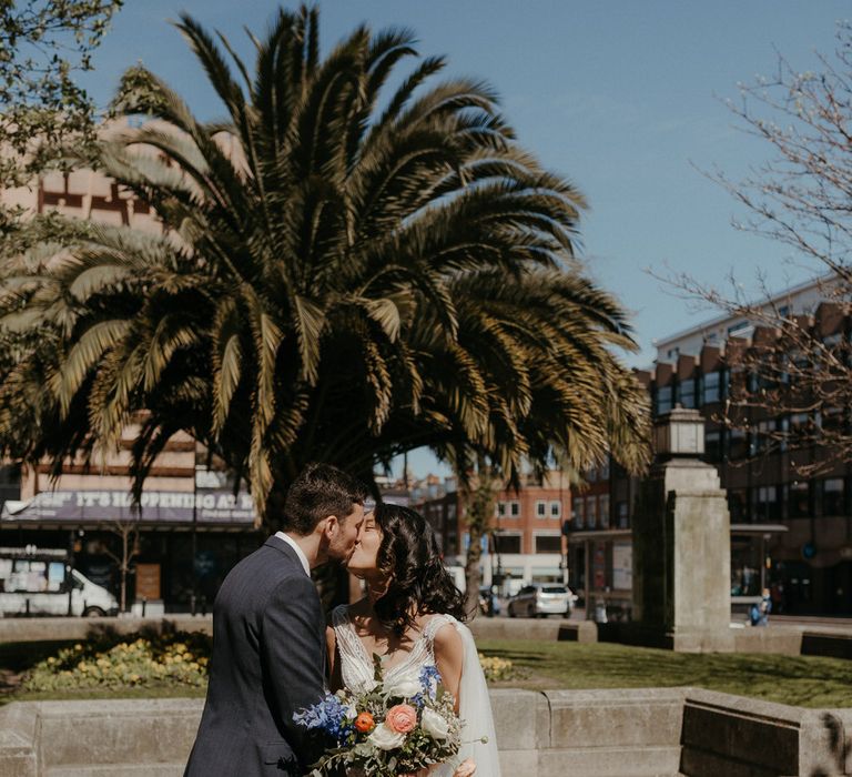 Bride and groom share a kiss outside Hackney Town Hall