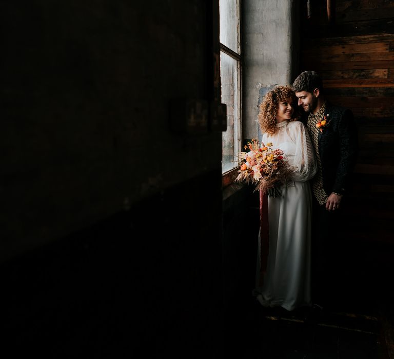 70s wedding inspiration in an industrial venue in Manchester with the bride in a jumpsuit and groom a patterned shirt 