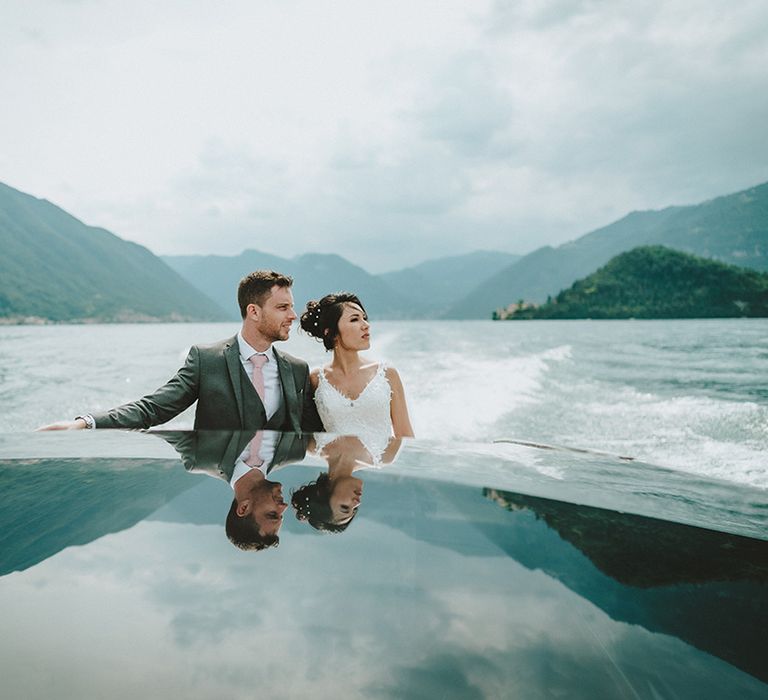 Bride & groom stand on boat as they sail across Lake Como on their wedding day