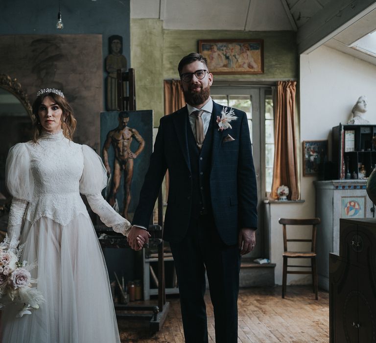 Bride & groom stand holding hands within the Charleston House as bride wears wedding gown inspired by the Labyrinth 