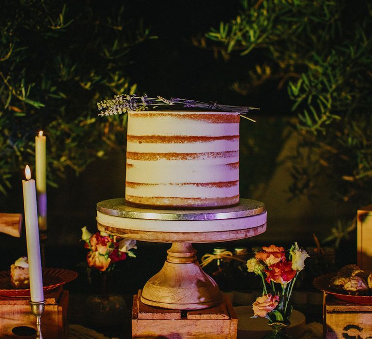 White naked wedding cake on wooden stand for dessert table