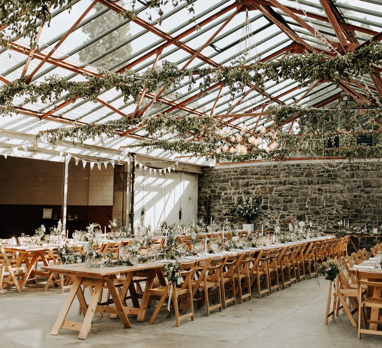 Rustic wedding venue with long wooden tables and foliage decor