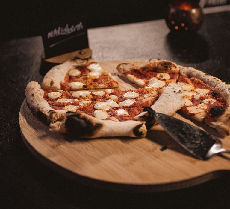 Rustic Margherita pizza on wooden pizza board at tipi wedding reception during Inkersall Grange Farm wedding