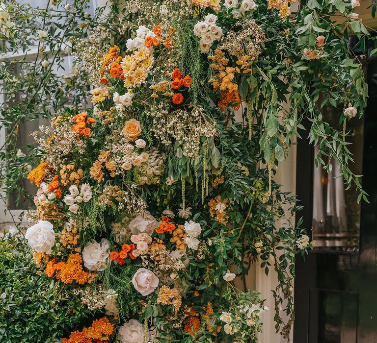 orange, peach and green wedding flower arrangement at the entrance to Modern Hall, London 