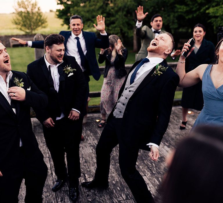 Wedding guests sing at outdoor wedding at Cripps Barn