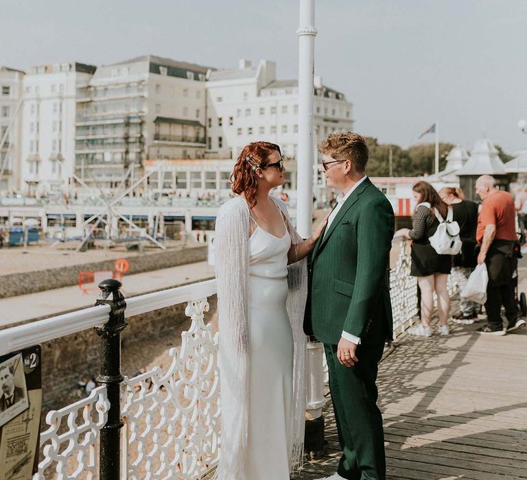 Bride & groom stand with one another near the beachfront of Brighton on their wedding day