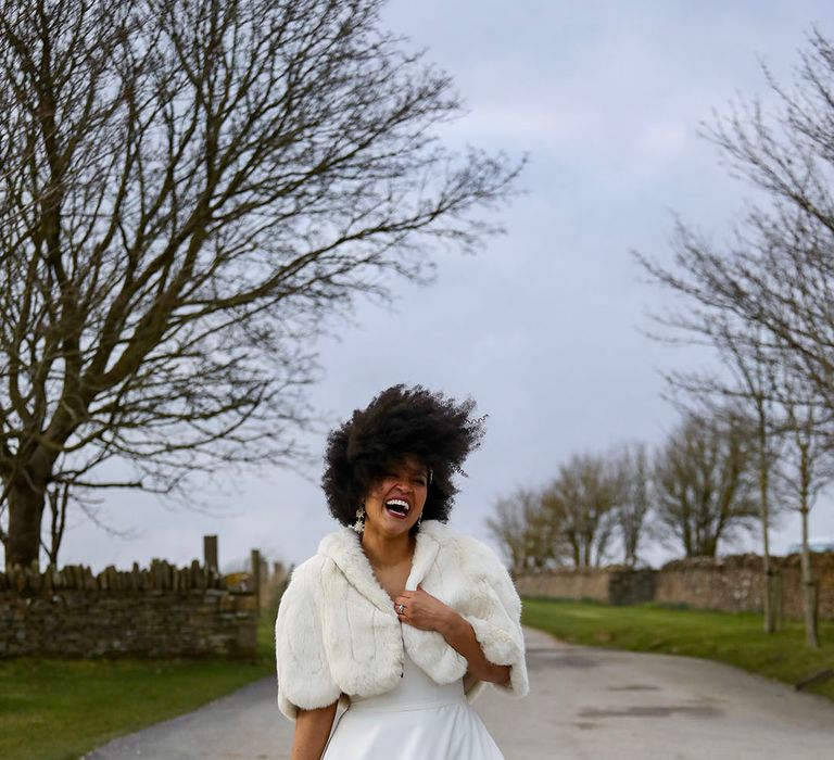 Bride wears faux fur shawl outdoors on her wedding day