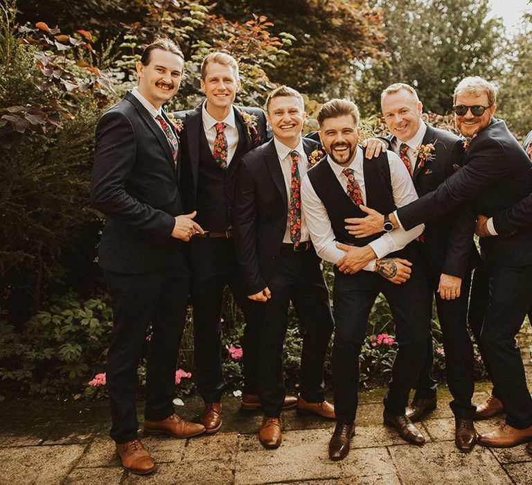 Groom and groomsmen in navy suits with floral Liberty print ties at back garden wedding 