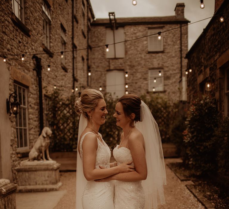 Brides look lovingly at one another on the day of their wedding