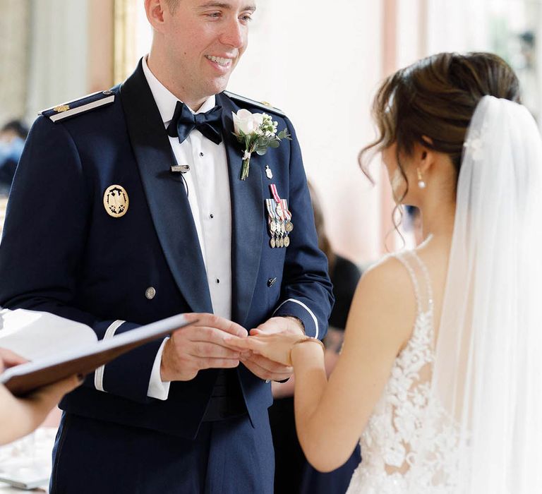 Groom wears Military Uniform and looks lovingly at his bride during wedding ceremony