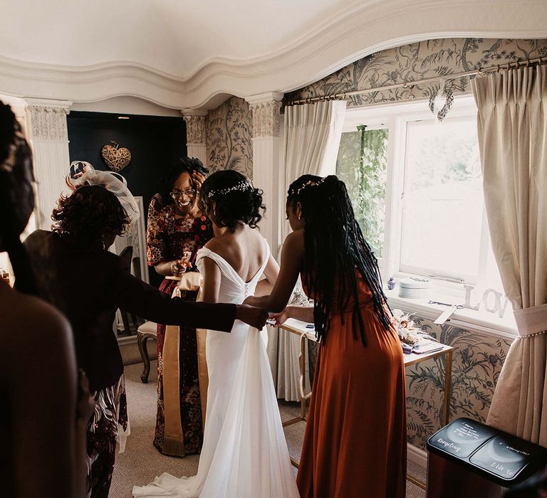 Bridesmaid does up brides gown on the morning of her wedding day