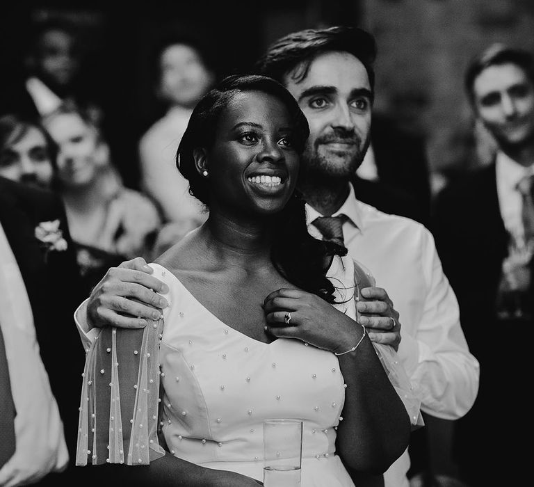 Black and white portrait of the groom holding his brides shoulders as they listen to the wedding speeches at their 100 Barrington wedding 