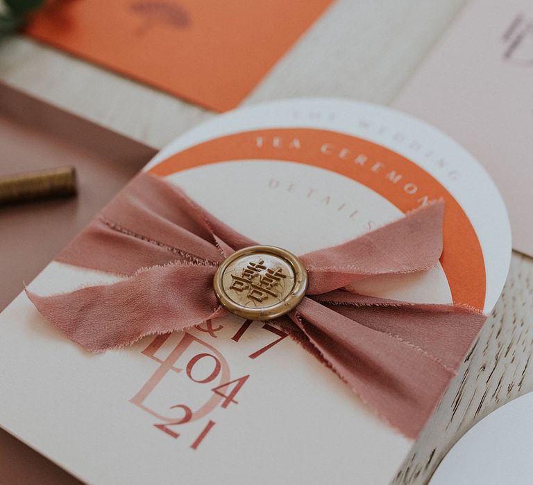 Orange and blush pink table setting cards with wax seal and ribbon