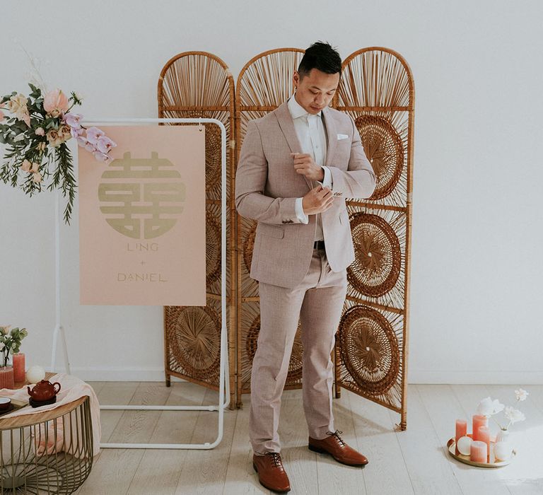 Groom in light linen suit surrounded by detailed modern asian wedding decor 