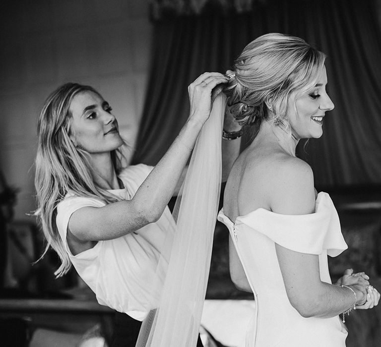 Bride gets her veil put in her blonde updo wearing off the shoulder white wedding dress