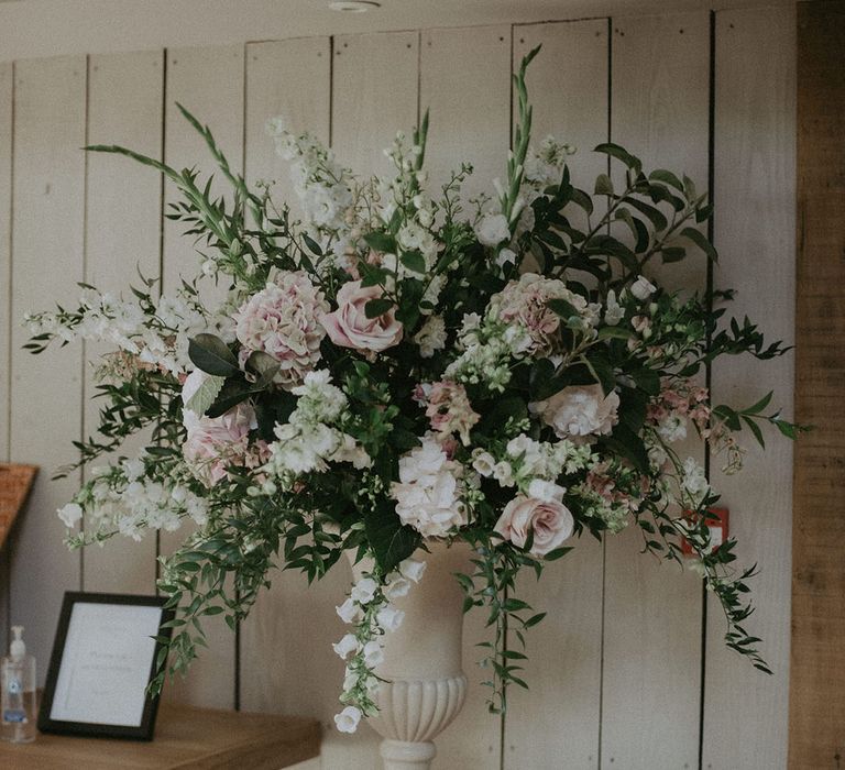 Pillar of pink, white and green flower displays with roses at contemporary barn venue 