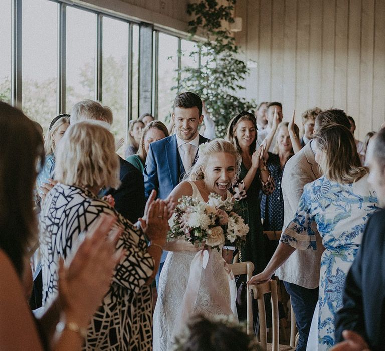 Bride and groom enter their wedding reception as a smiling married couple at barn venue