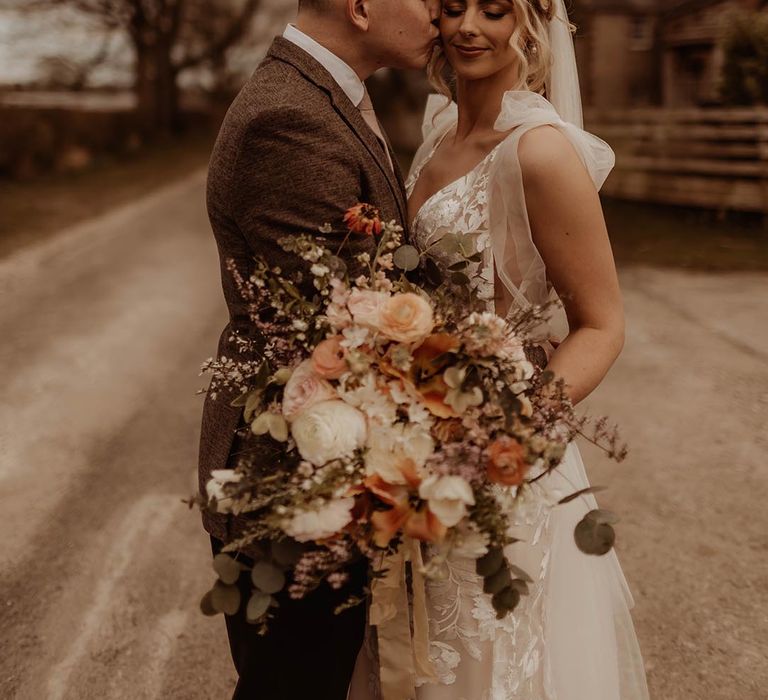 Groom kisses the bride on the cheek after their barn wedding ceremony with bride wearing Made With Love Elsie dress