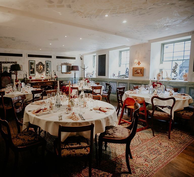 Round table with white tablecloths decorated with pink napkins and dark red ribbon and other details for The Zetter Townhouse 