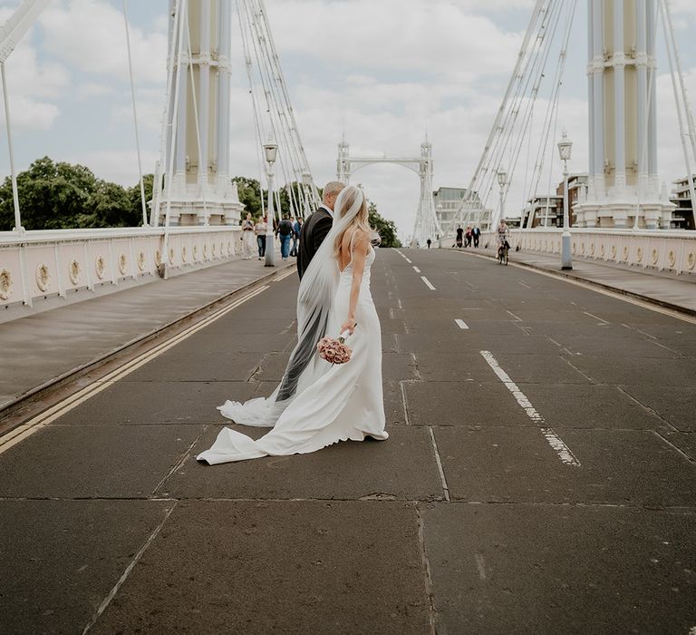 Bride and groom walk across a bridge in London on their wedding day