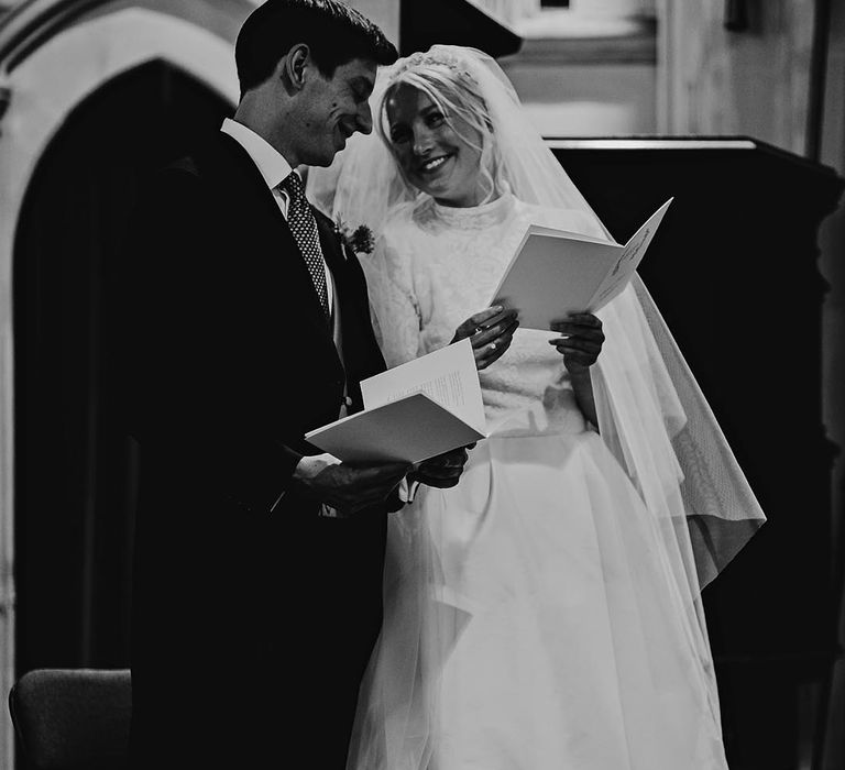 Bride and groom smile at each other as they stand for their church wedding ceremony 