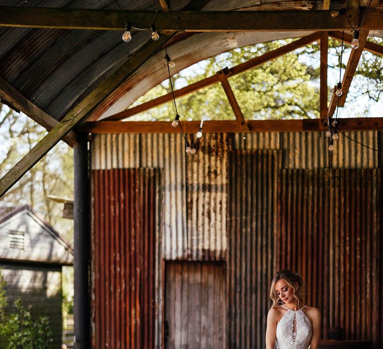 Bride in halter neck floral wedding dress with long train carrying pink and white bridal bouquet 