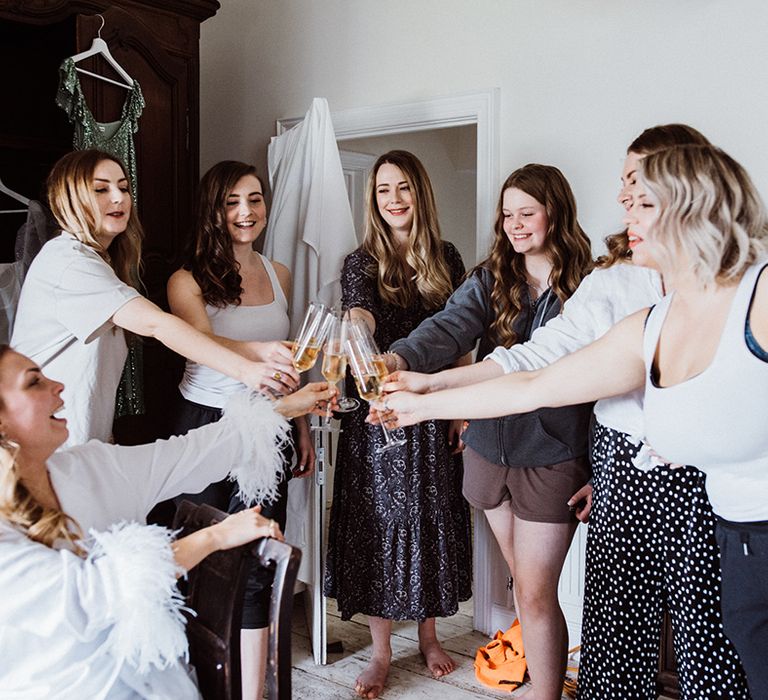 Bridesmaids and the bride make a cheers together as they get ready for the wedding 