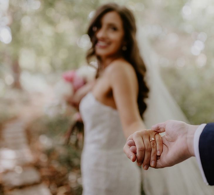 Bride walks hand in hand with her groom and wears gold band wedding ring with diamond 