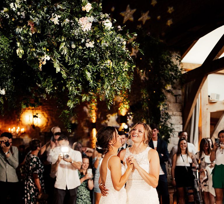 Brides do their first dance together as the guests watch on 