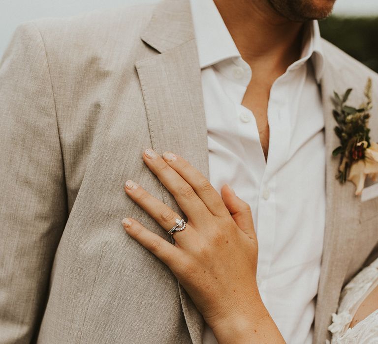 Bride's silver engagement ring and wedding band with colourful flower pattern nails with the groom in a light suit 