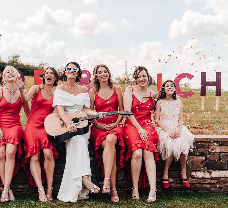 Bride in ASOS wedding dress with bridesmaids in vibrant ruffle dresses and flower girls in tulle pink dresses