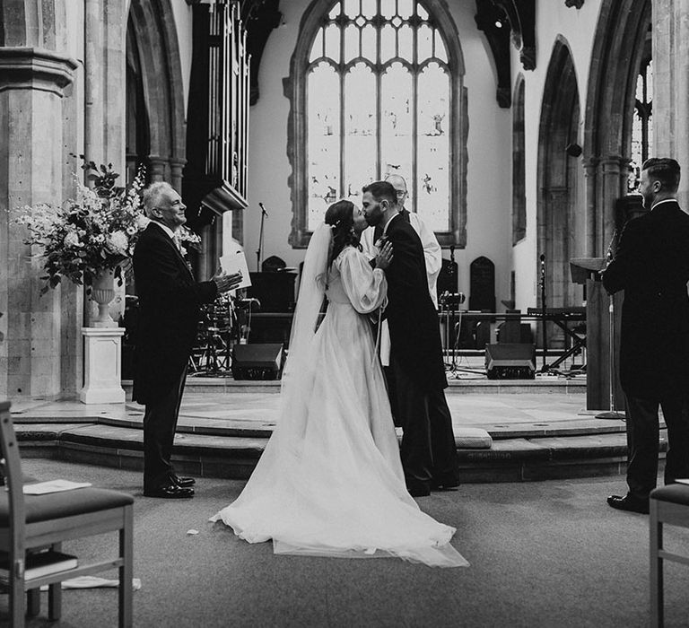 Bride and groom share their first kiss as a married couple at their church wedding ceremony 