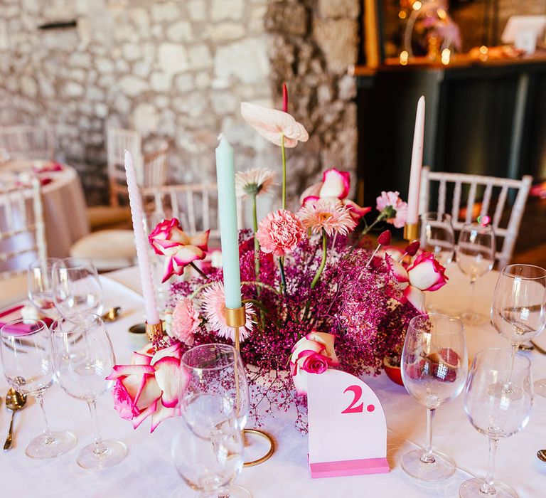 Bright magenta wedding flower centrepiece with pastel blue taper candles 