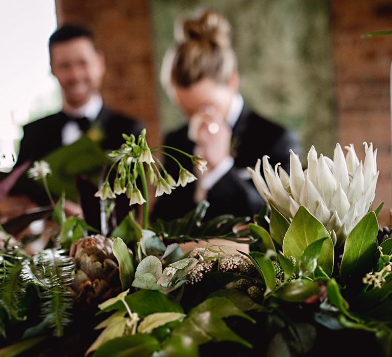 Botanical decor complete with white florals and green foliage on wooden table