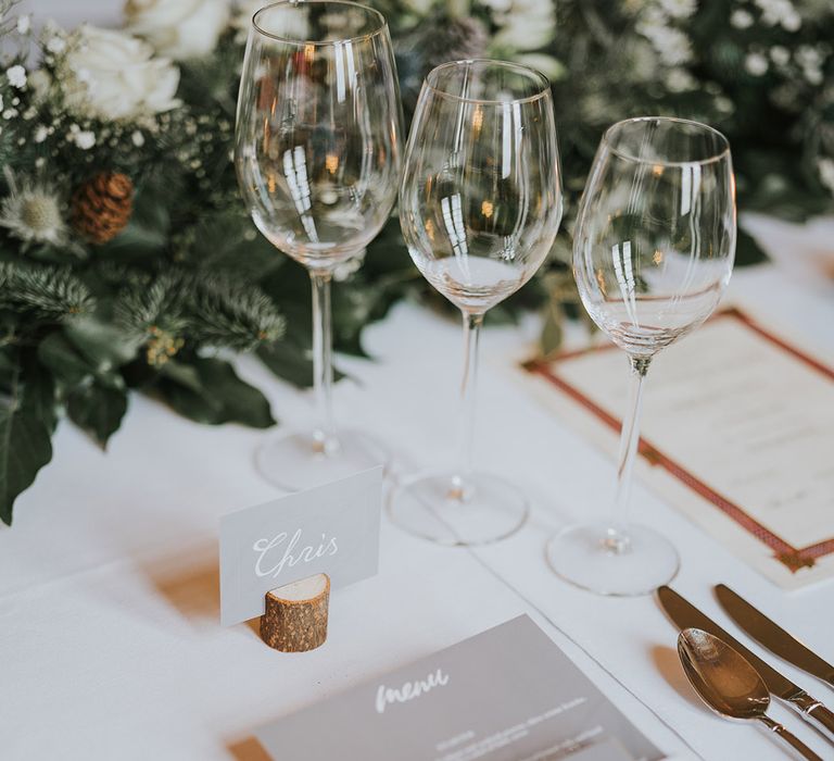 Grey and white place names and wedding stationery and gold cutlery with foliage and white flowers 