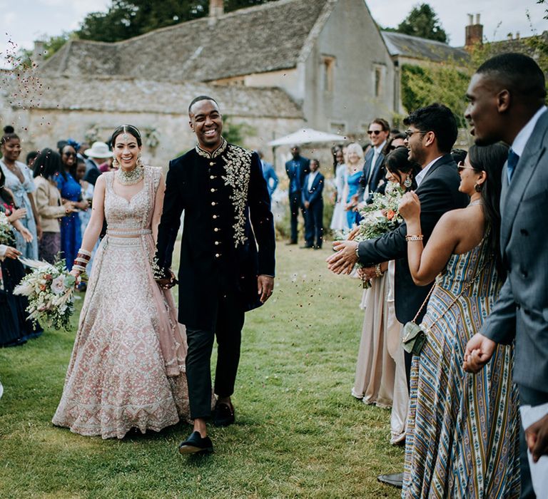 Bride and Groom walk through confetti throw at Cotswolds wedding venue, Caswell House