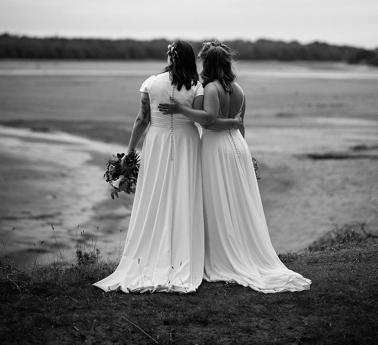 Black and white couple portrait of the two brides resting their arms around each other looking out at the views 