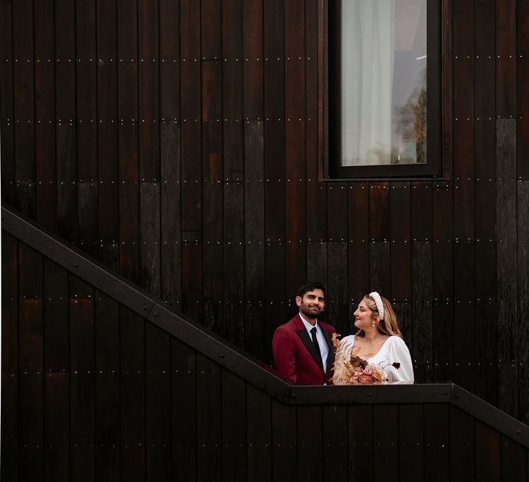 The bride and groom pose for their couple portraits together in front of the black cladding at their wedding venue 