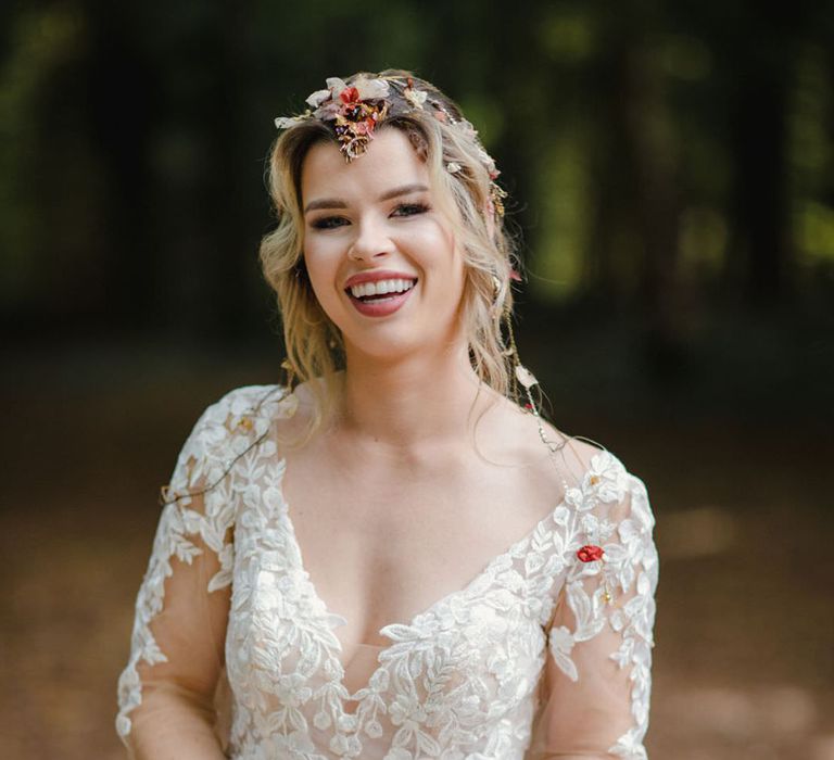 Bride laughing and smiling in long sleeved v neck soft ivory dress with botanical embroidered details holding dried autumnal wedding bouquet and wearing headpiece with delicate details and mix of soft gold & bronze metals