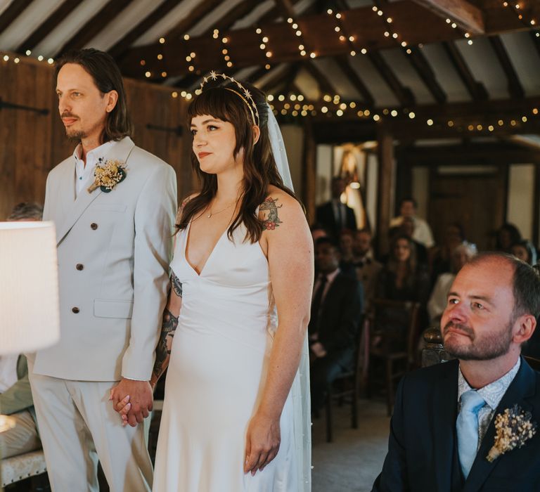 Bride and groom at the alter of Essex wedding venue with firelights decorations in the beams 